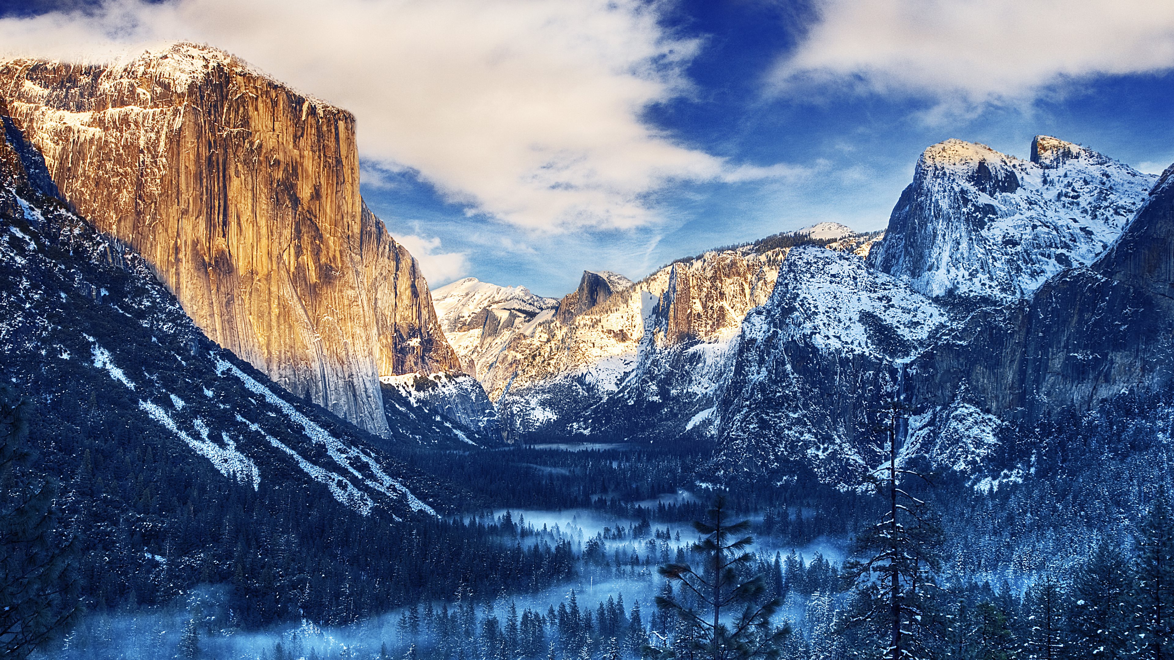 4k background of a breathtaking winter landscape in Yosemite Valley, featuring snow-capped granite cliffs, a misty valley floor, and a vibrant blue sky