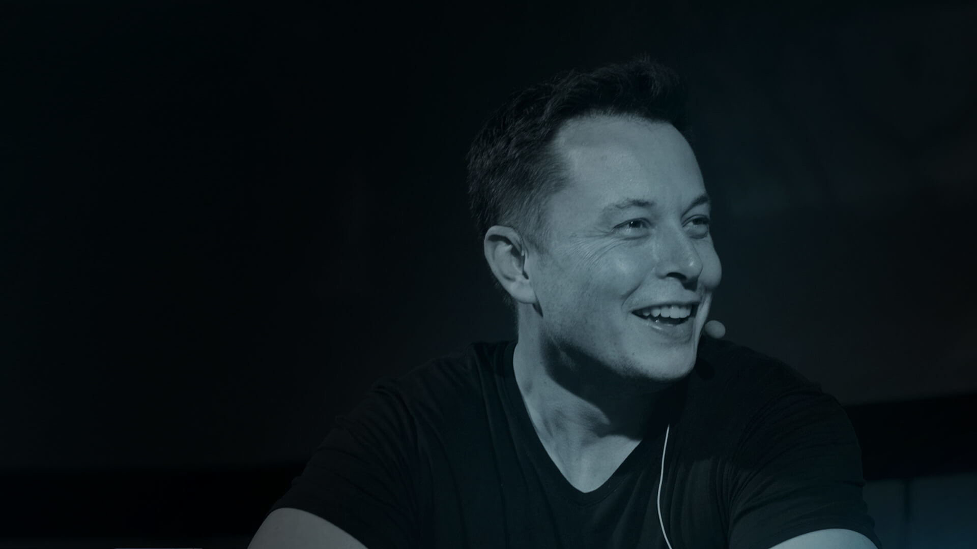 Elon Musk smiling during a speaking engagement, captured in a high-quality, close-up shot