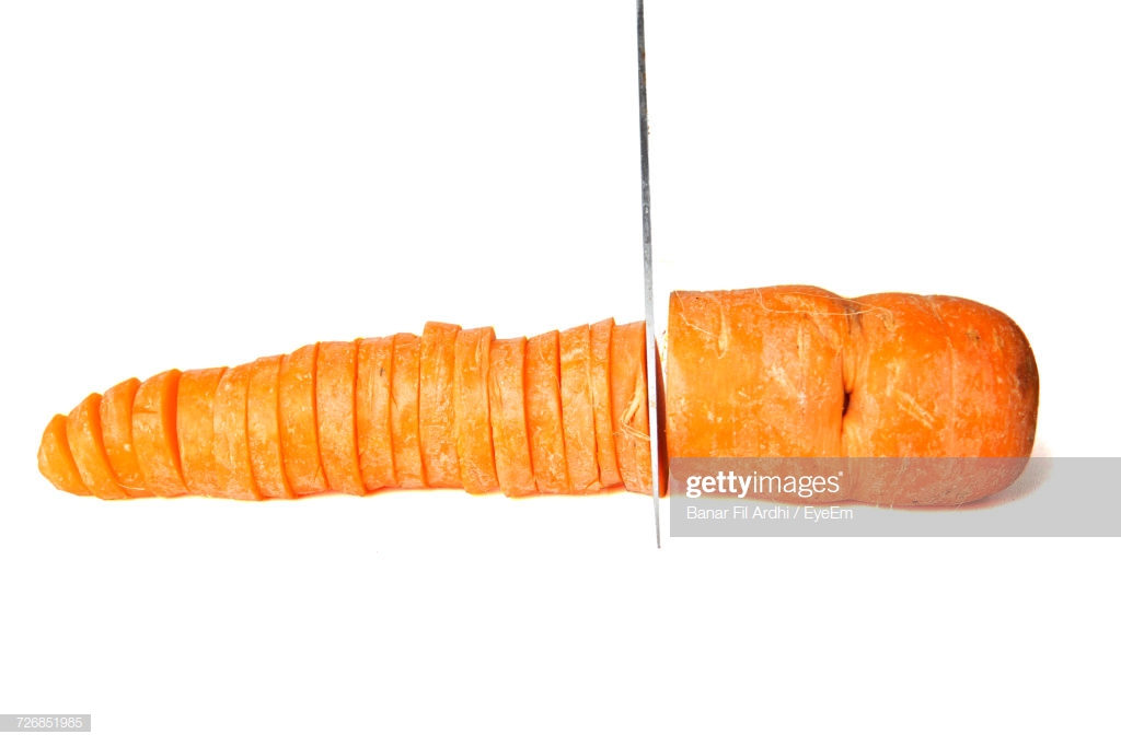 Knife On Chopped Carrot Against White Background Stock Photo