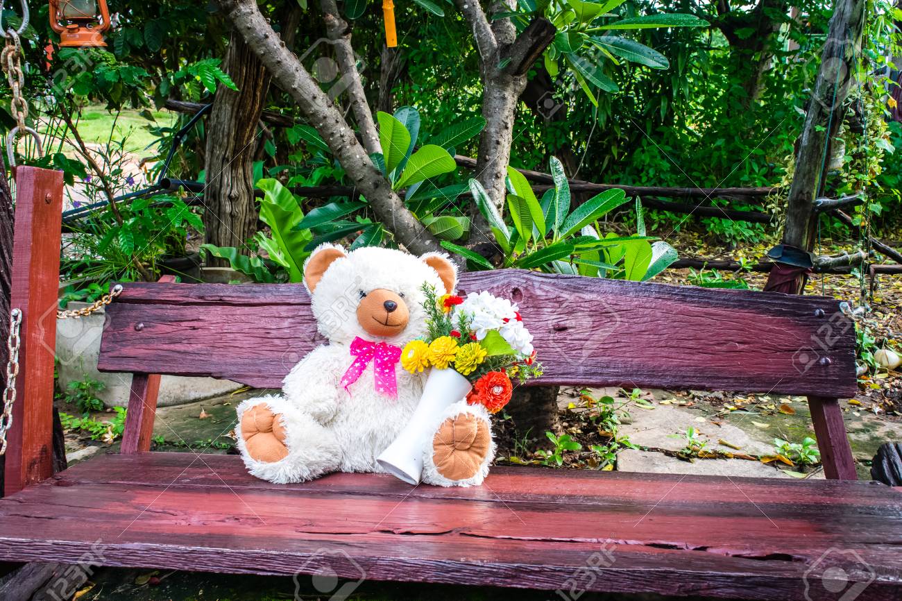 Alone Teddy Bear Sitting On Wooden Swing With Flower Nature