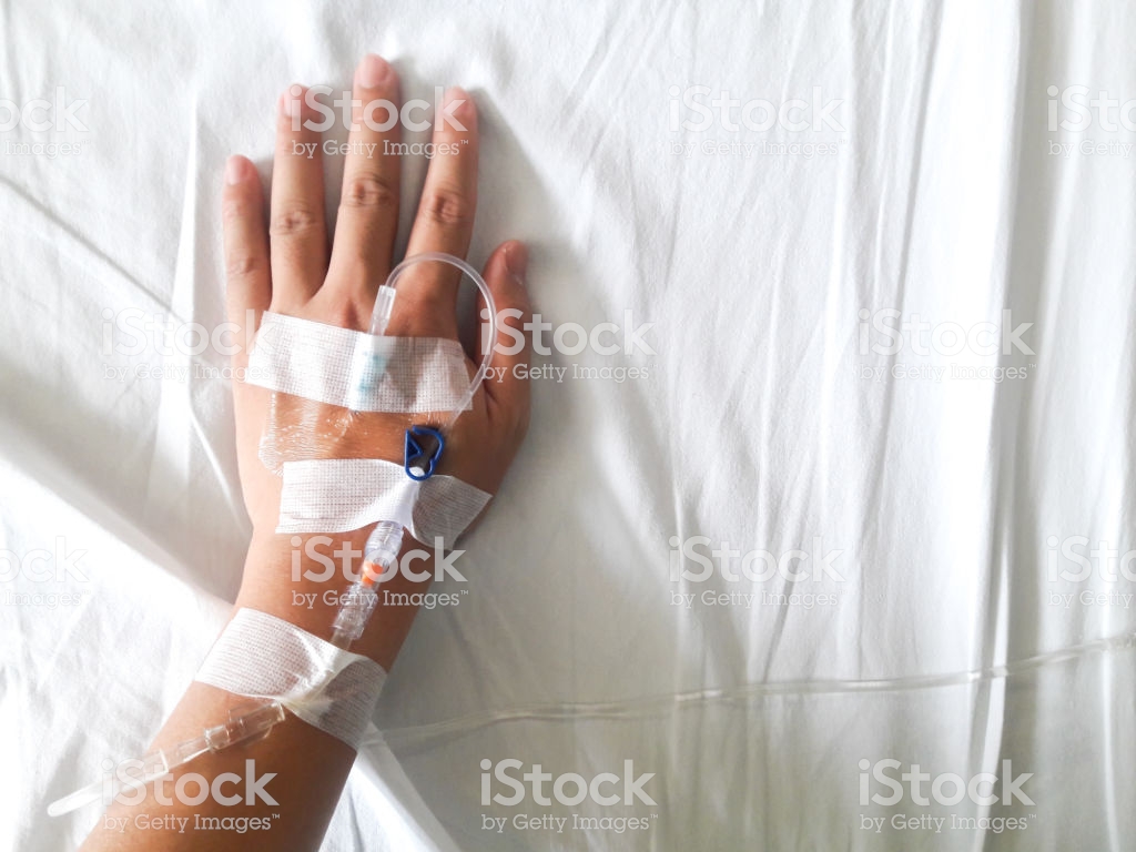 Patient Hand With The Tube Of Normal Saline Infusion On White