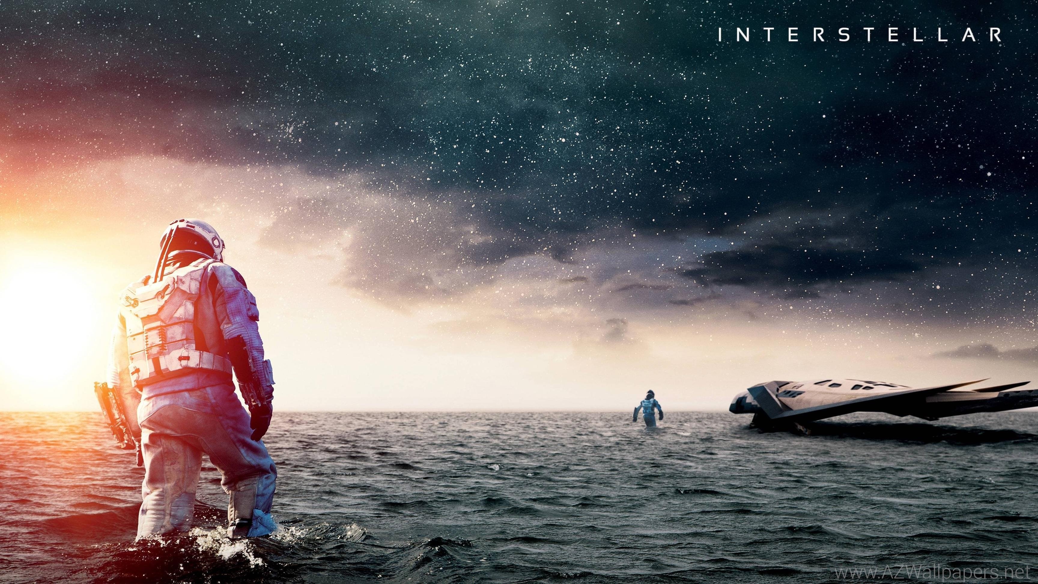 Astronauts wading in shallow water towards a futuristic spacecraft, with a starry sky in the background, from the movie Interstellar