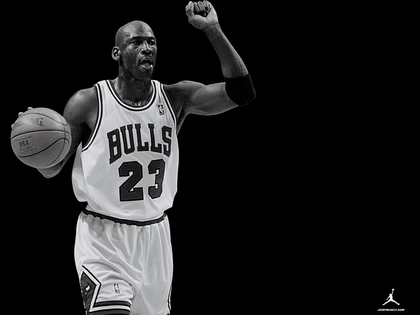 Black and white image of Michael Jordan in a Chicago Bulls uniform, holding a basketball and raising his fist in celebration