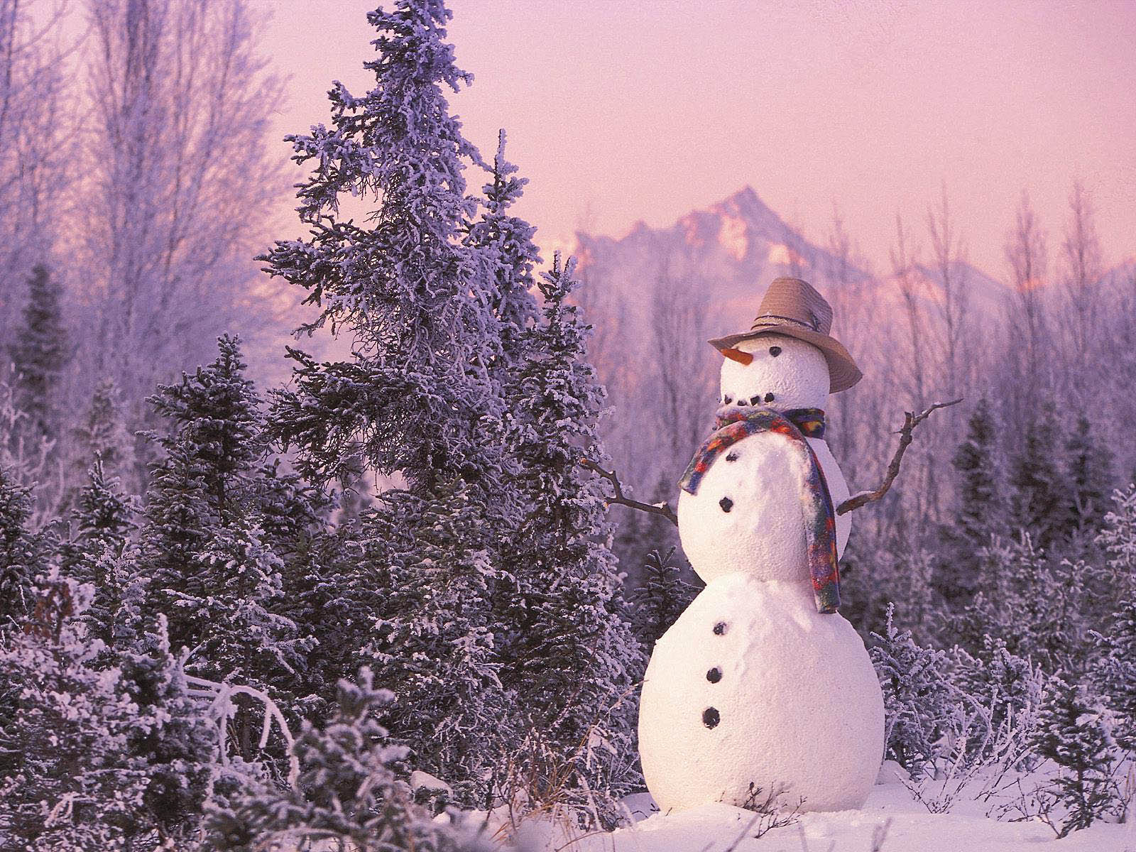 A classic snowman stands proudly amidst a snowy forest scene, complete with a hat and scarf, against the backdrop of a majestic mountain range