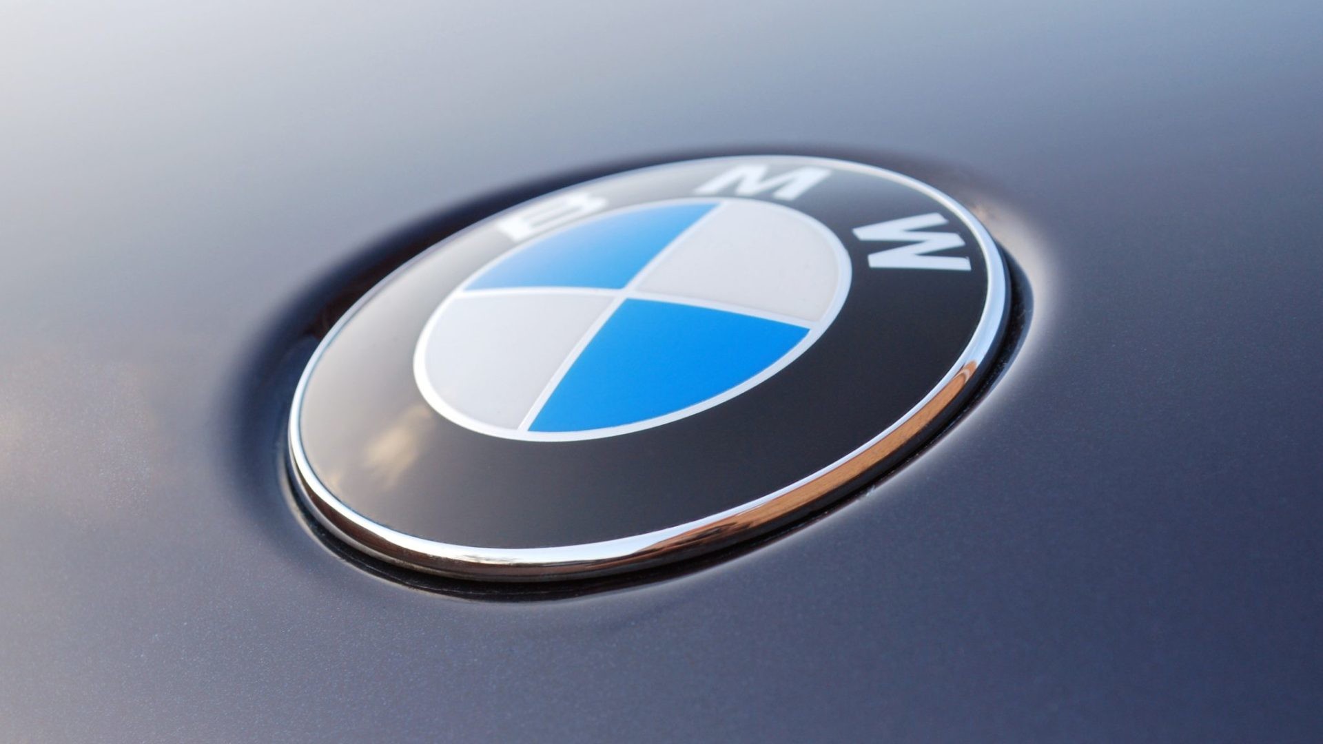 Close-up of a BMW logo on a car, showcasing the iconic blue and white roundel against a dark background