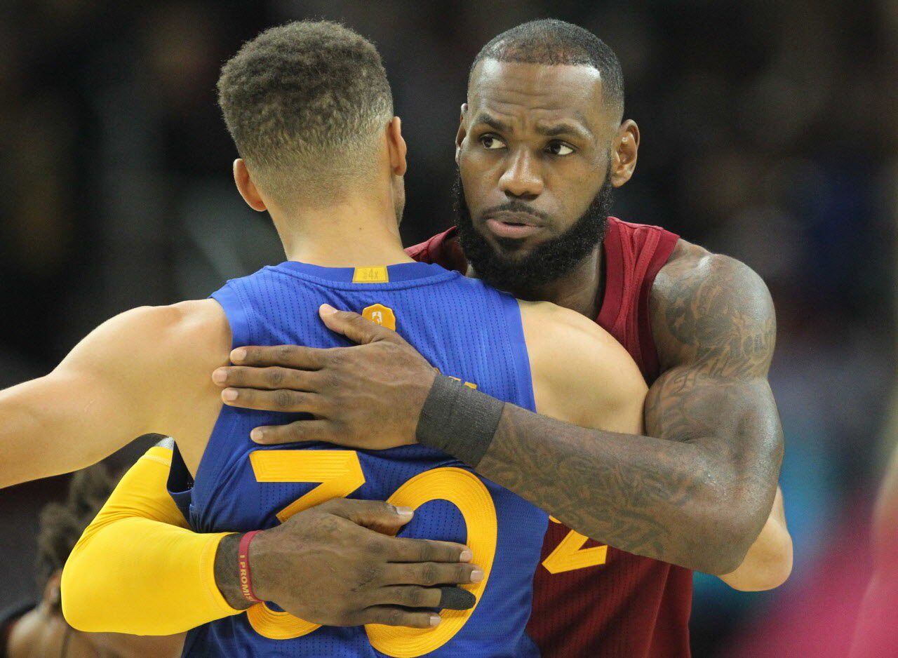 LeBron James and Stephen Curry embrace during a basketball game, showcasing sportsmanship and mutual respect