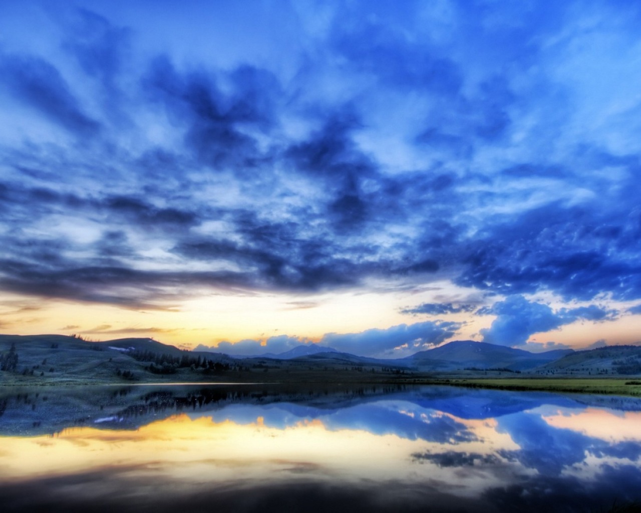 Stunning sunset over a serene lake reflecting the colorful sky and surrounding mountains