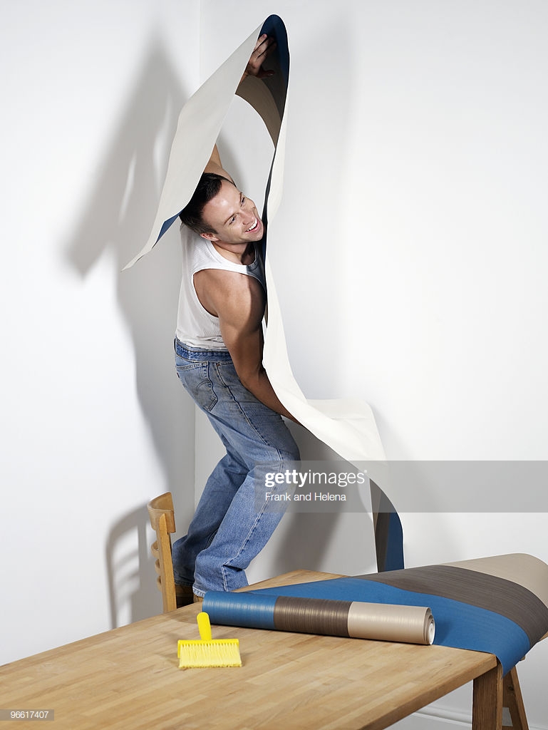 Smiling Man Struggling With Wallpaper Stock Photo Getty Image