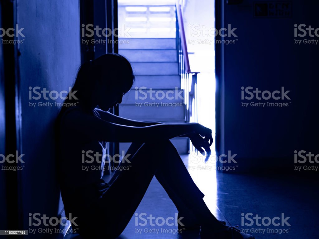 Silhouette Of A Sad Young Girl Sitting In The Dark Leaning Against