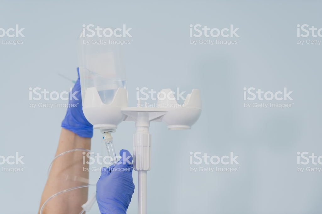 Doctors Hands And Infusion Drip In Hospital On Blurred Background
