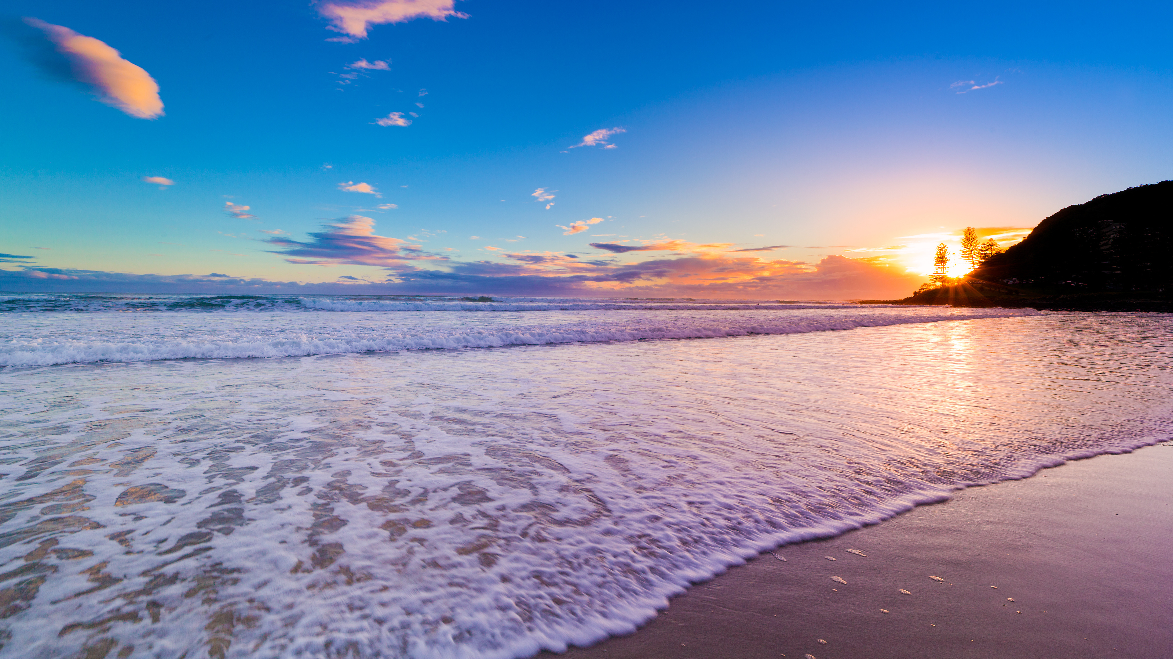 Sunrise over a pristine beach with gentle waves, 4K scenery wallpaper