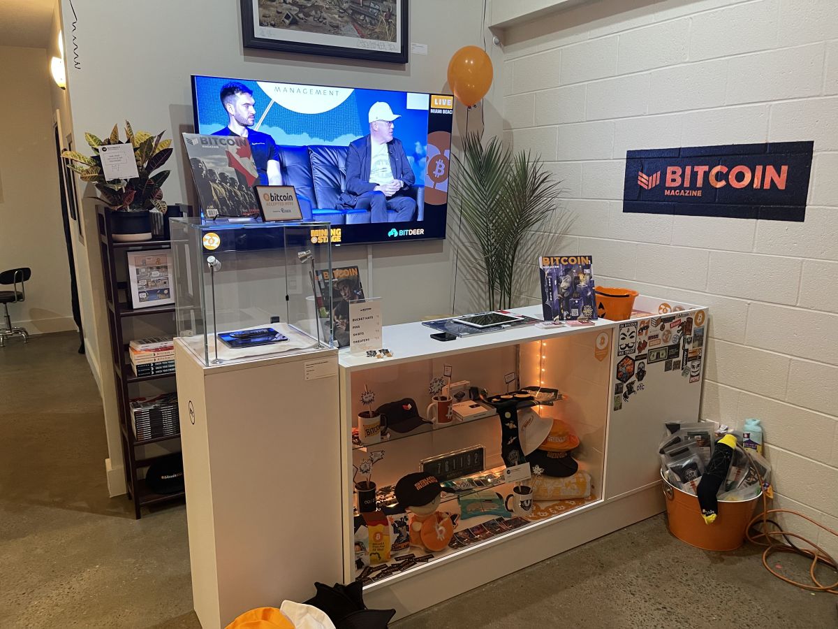 A display booth showcasing Bitcoin Magazine merchandise and content at a Bitcoin conference or event