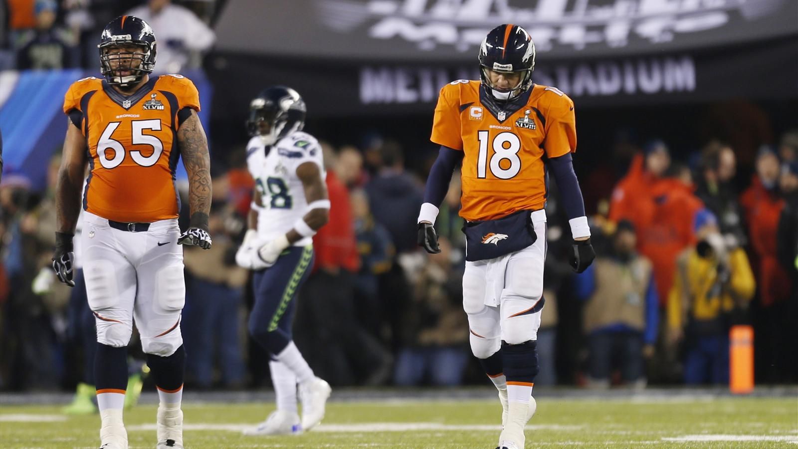 Denver Broncos quarterback Peyton Manning walks with teammate