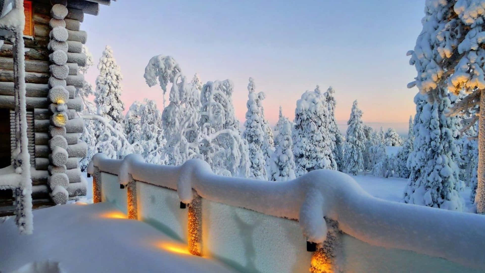 A breathtaking 4K wallpaper showcasing a snow-covered cabin in a winter wonderland. The warm glow of lights from the cabin contrasts beautifully with the frosty landscape, creating a cozy and magical atmosphere