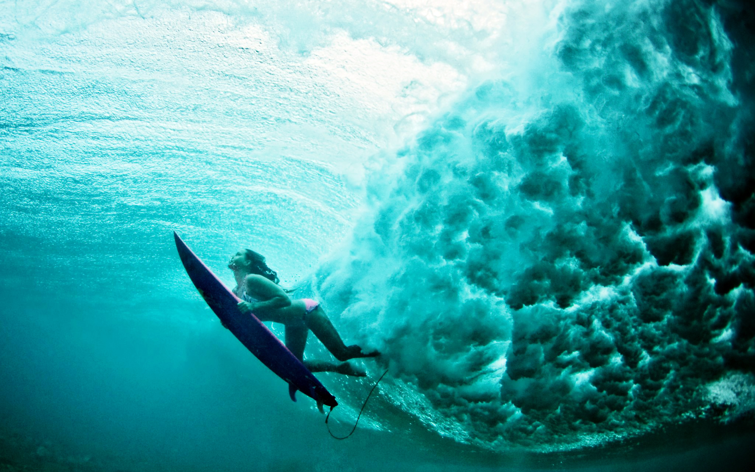 A surfer glides through a turquoise wave, captured from an underwater perspective, creating a dynamic and captivating surfing image