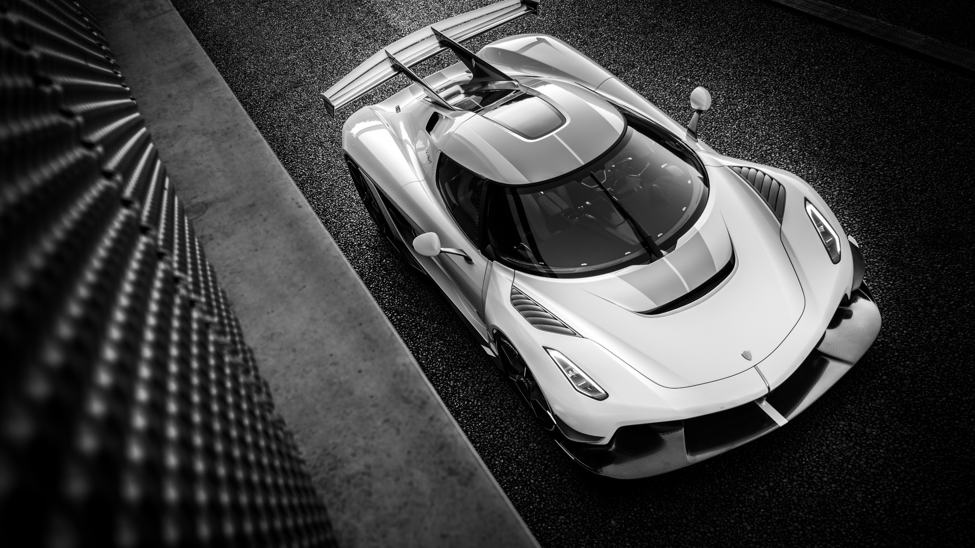 Black and white photo of a Koenigsegg Jesko parked next to a textured wall