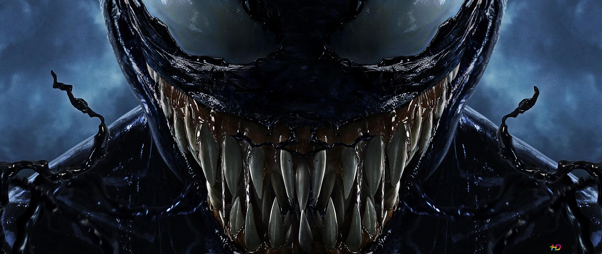 Close-up of Venom's menacing face with sharp teeth and swirling symbiote tendrils, from the movie Venom
