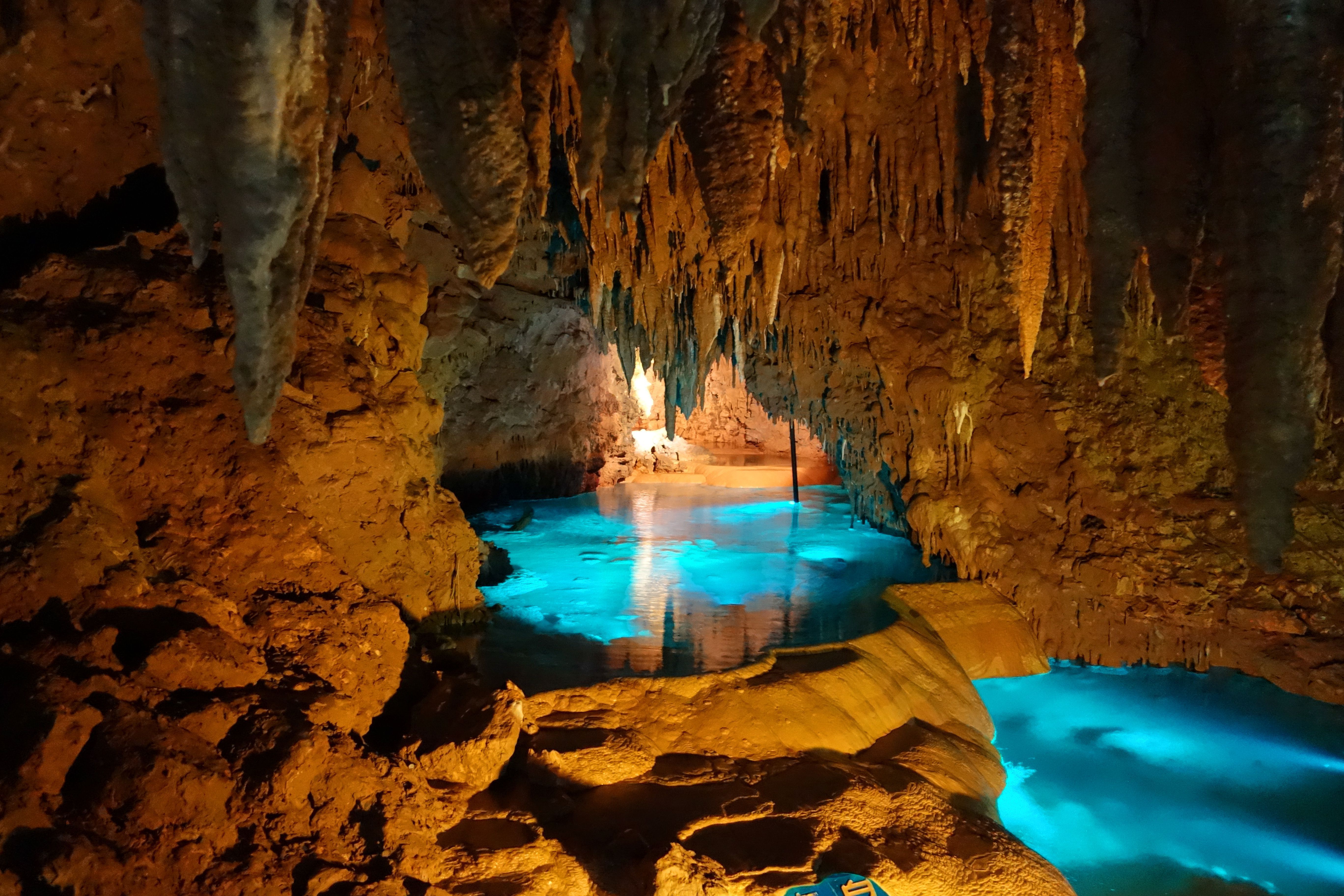 A mesmerizing view of an underground cave with crystal-clear turquoise water reflecting the cave's formations