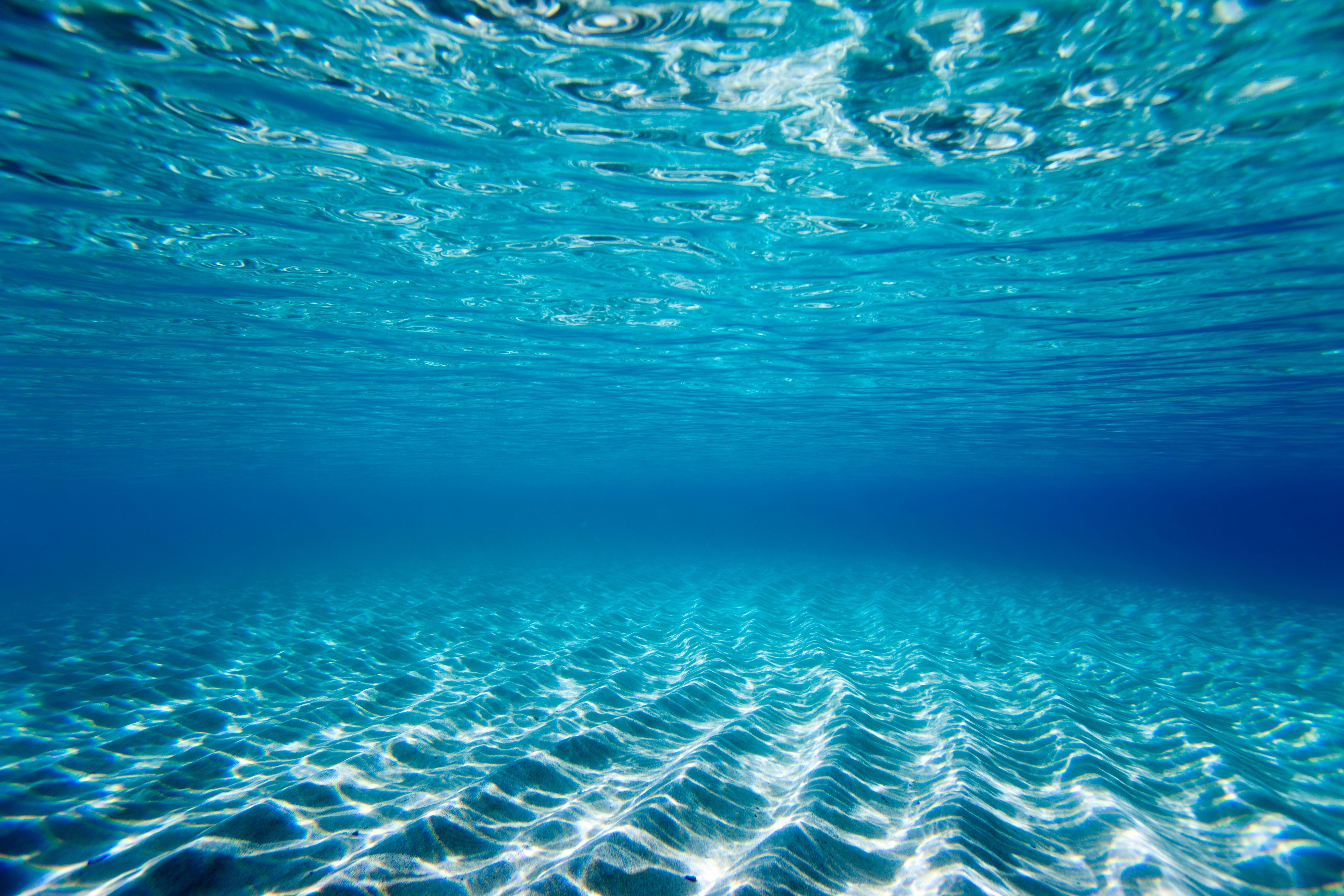 Tranquil underwater scene with rippling sand and clear blue water