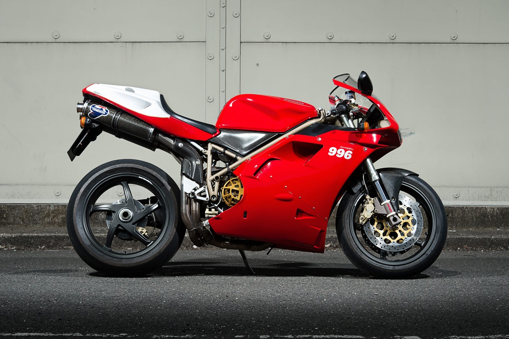 Ducati 996 sportbike parked on the road against a gray wall
