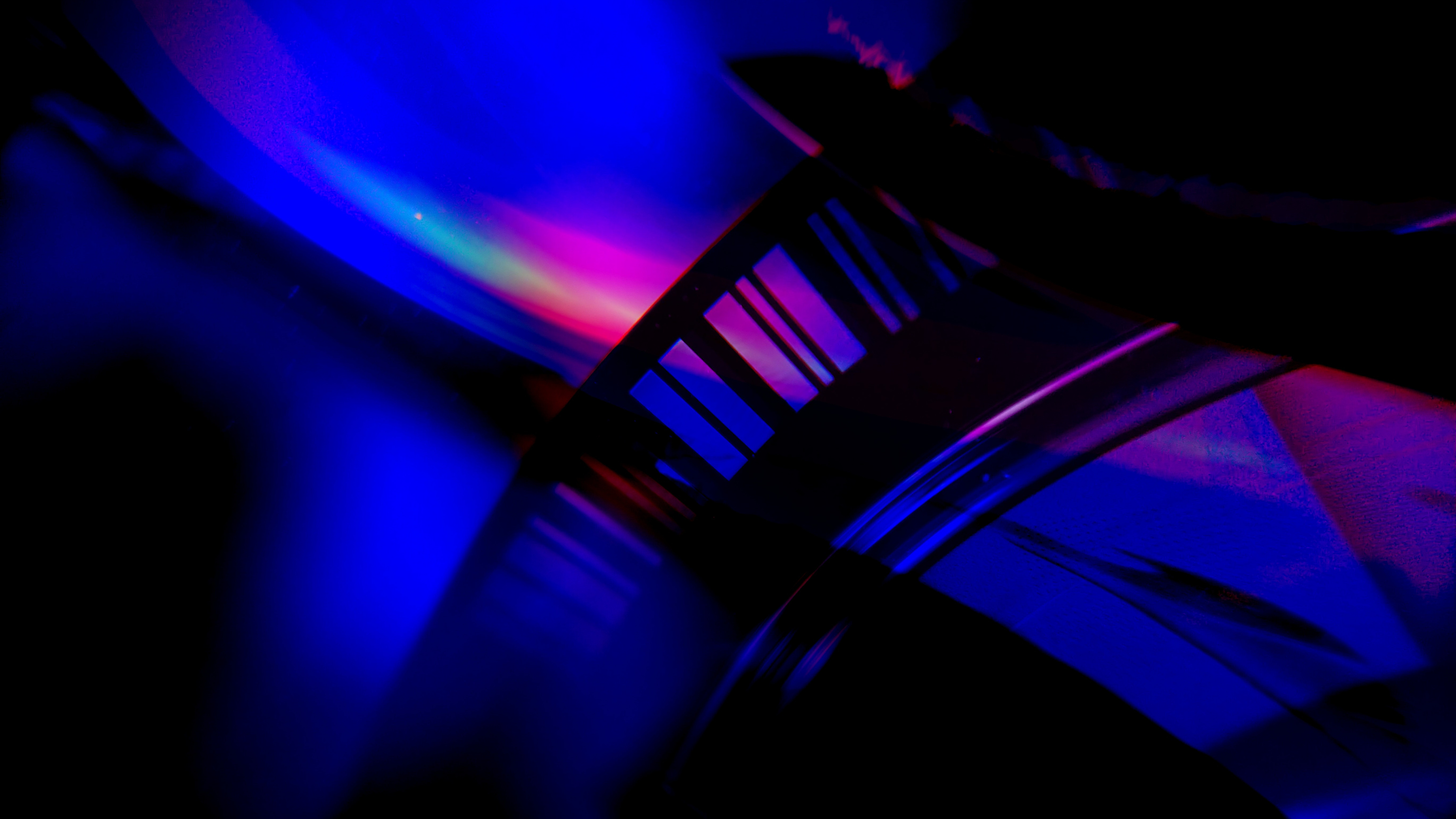 Abstract close-up of a film reel illuminated by vibrant neon lights, showcasing the interplay of light and shadow