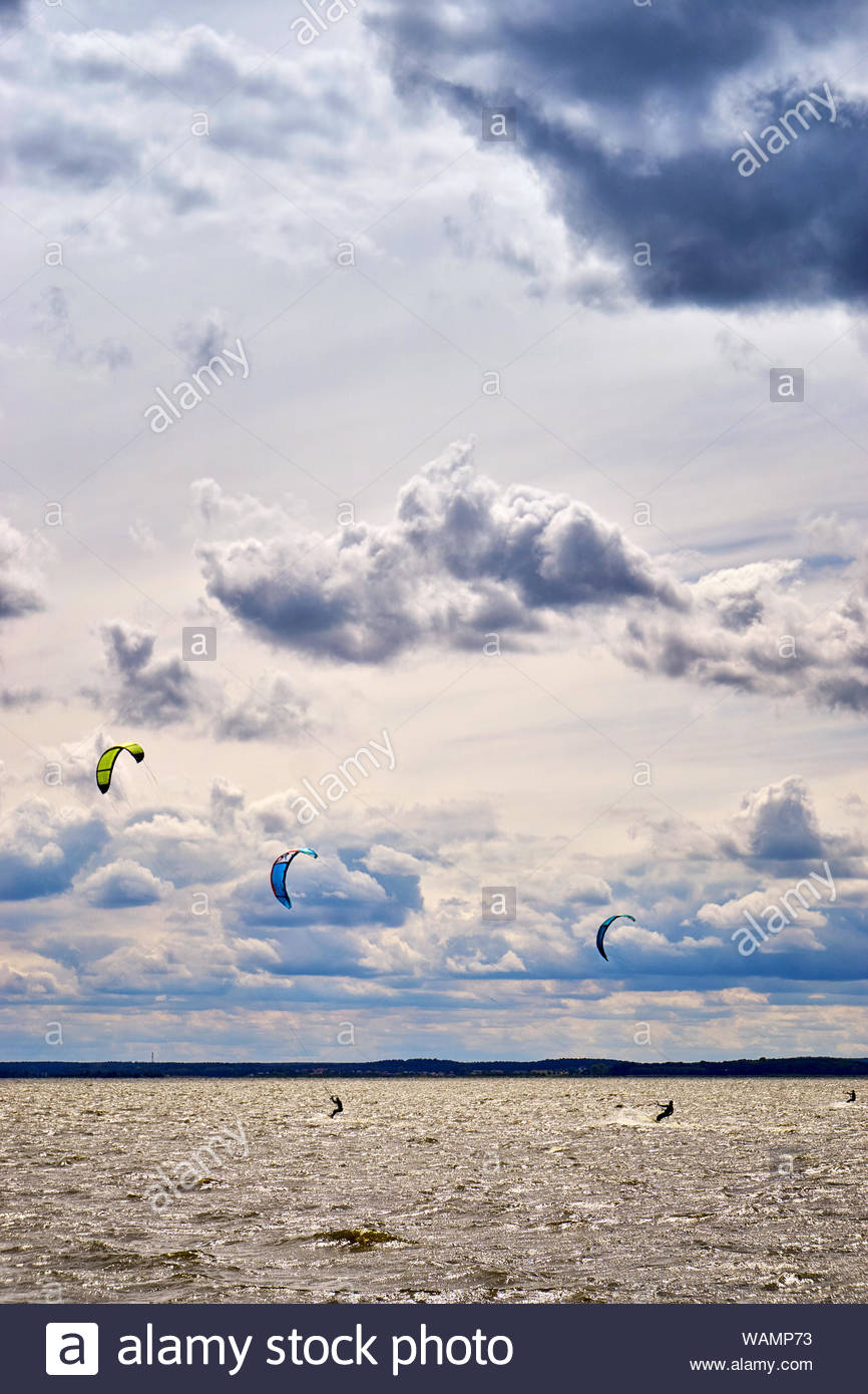 Three Men In Kiteboarding Kitesurfing On The Sea With Beautiful