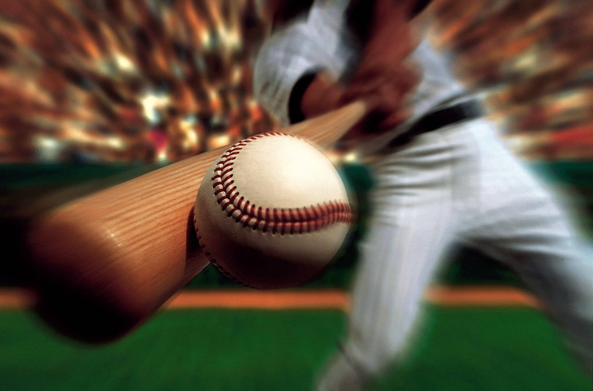 A baseball player swings his bat, making contact with the ball in a dynamic close-up shot. The blurred background suggests the speed and intensity of the game