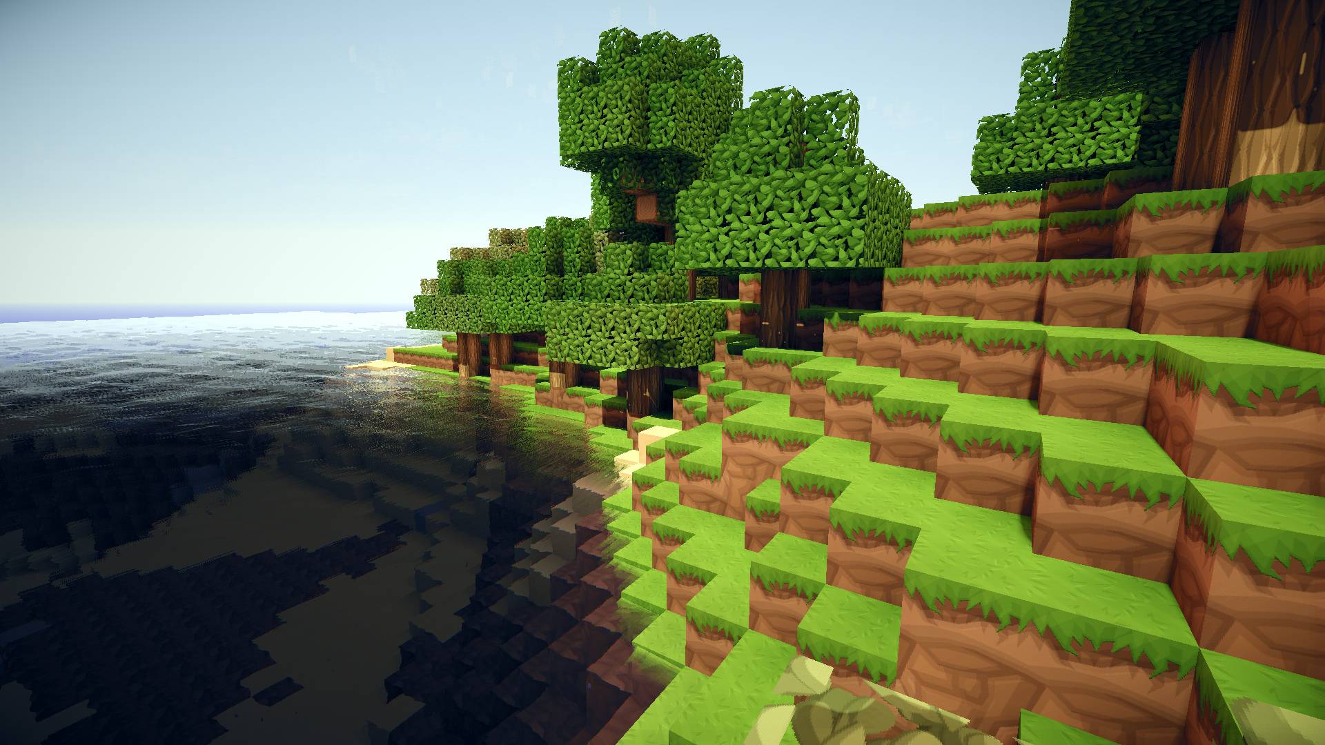 HD Minecraft wallpaper of a lush green hillside sloping down to a dark blue ocean, with pixelated trees and grass blocks