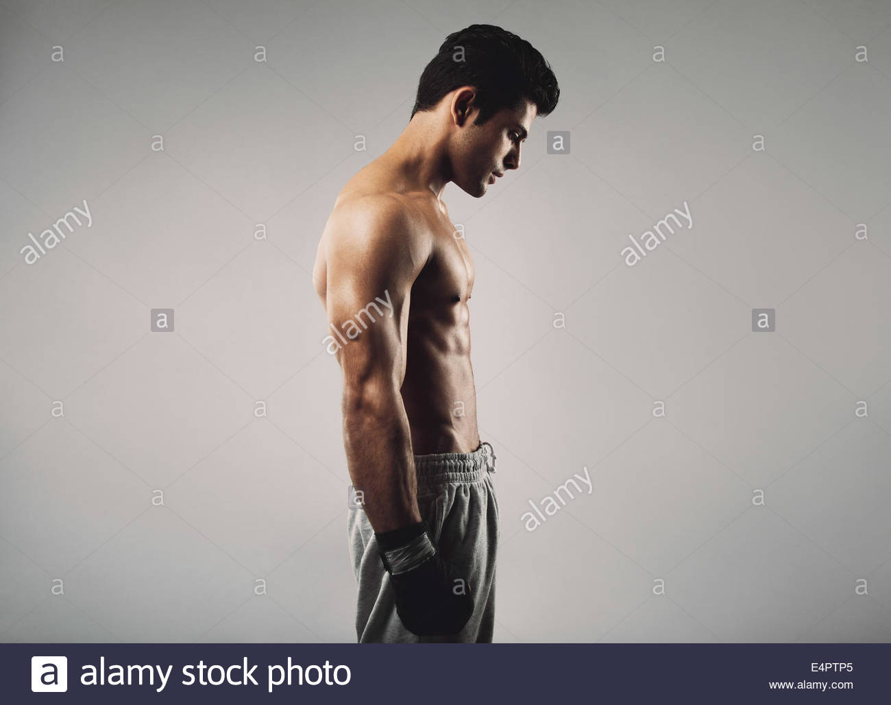 Side Of Fit Young Man Wearing Boxing Gloves Looking Down On