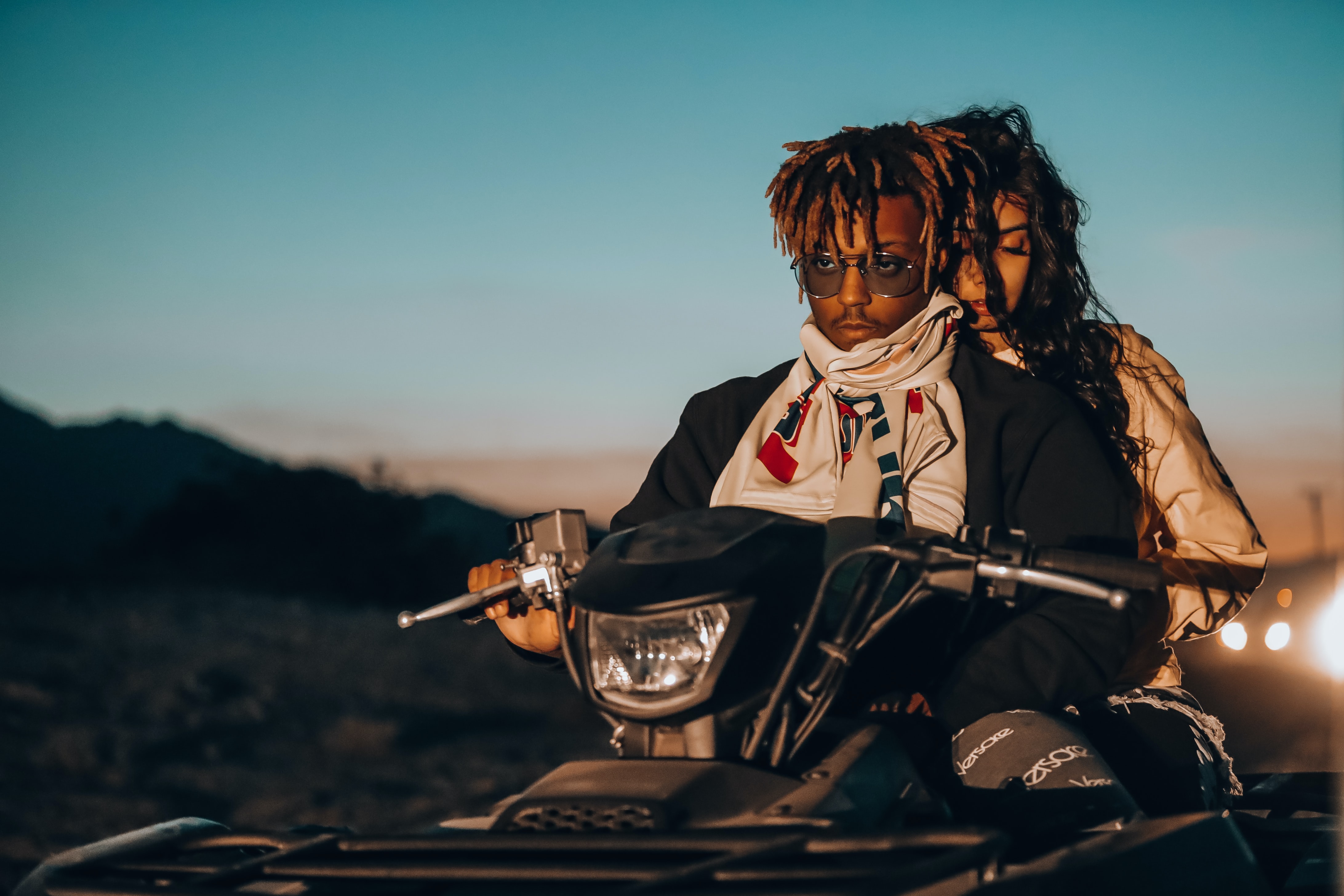 Juice WRLD riding an ATV with a woman at sunset in a desert landscape