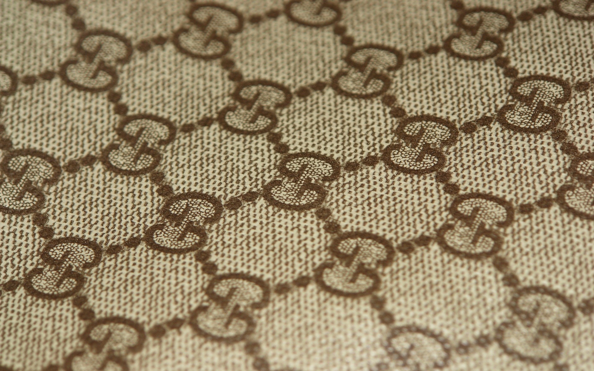 Close-up of beige Gucci GG canvas fabric, showcasing the interlocking G logo pattern
