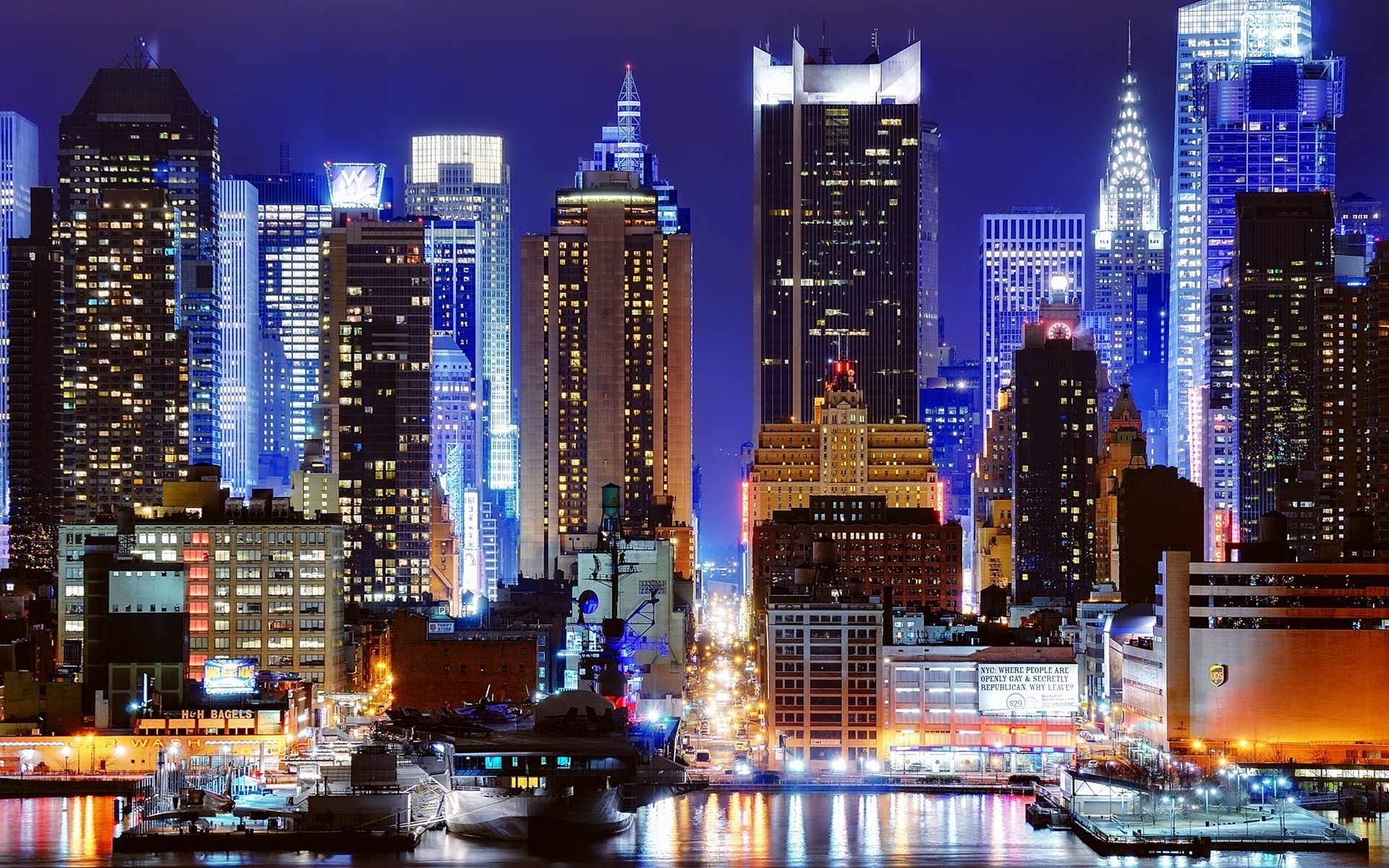 New York City skyline at night with illuminated buildings and reflections in the water