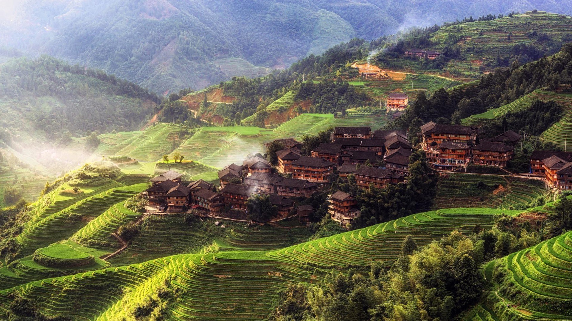 Traditional Chinese village nestled among lush green rice terraces in the mountains