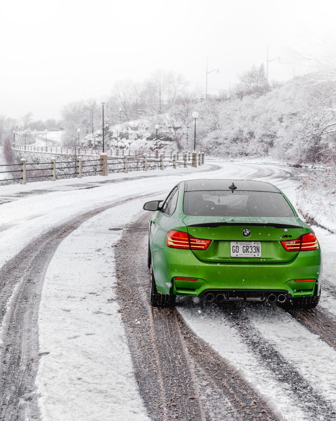 Green BMW M4 driving on a snowy road