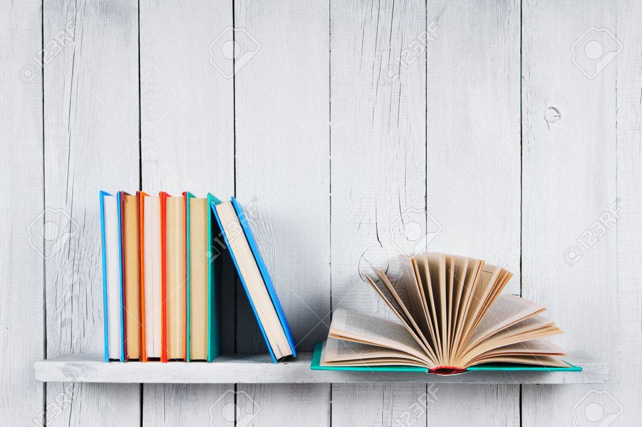 The Open Book And Other Multi Coloured Books On A Wooden Shelf