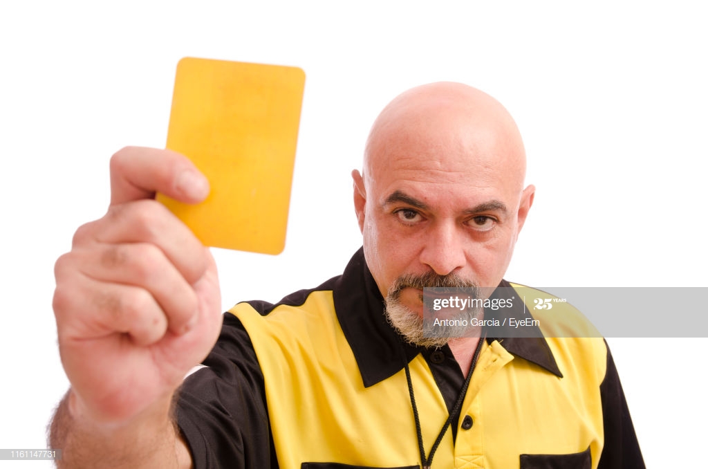 Portrait Of Referee Holding Yellow Card Against White Background