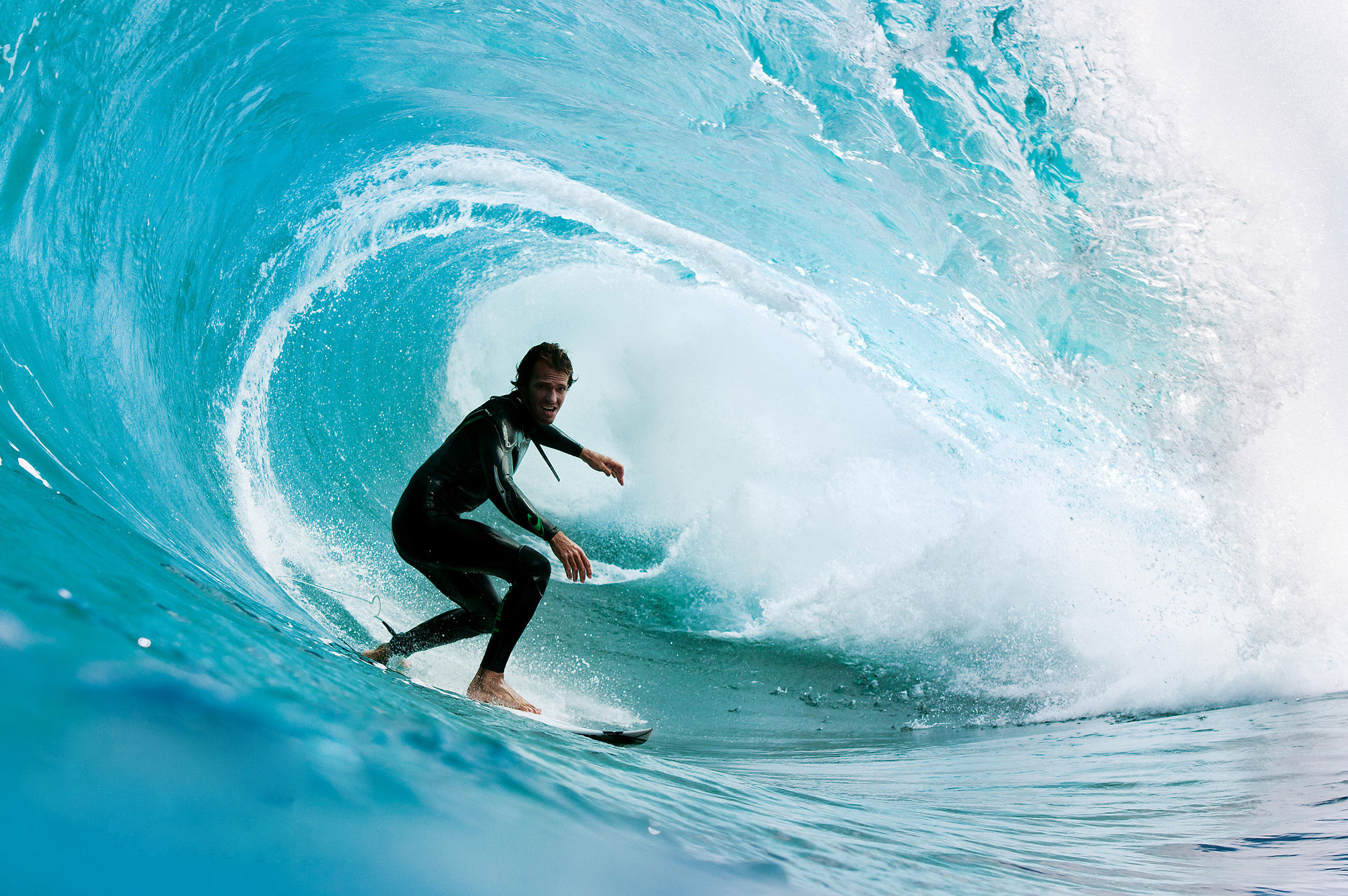 A surfer rides a powerful wave in a dynamic surfing action shot, perfect for a surfing wallpaper