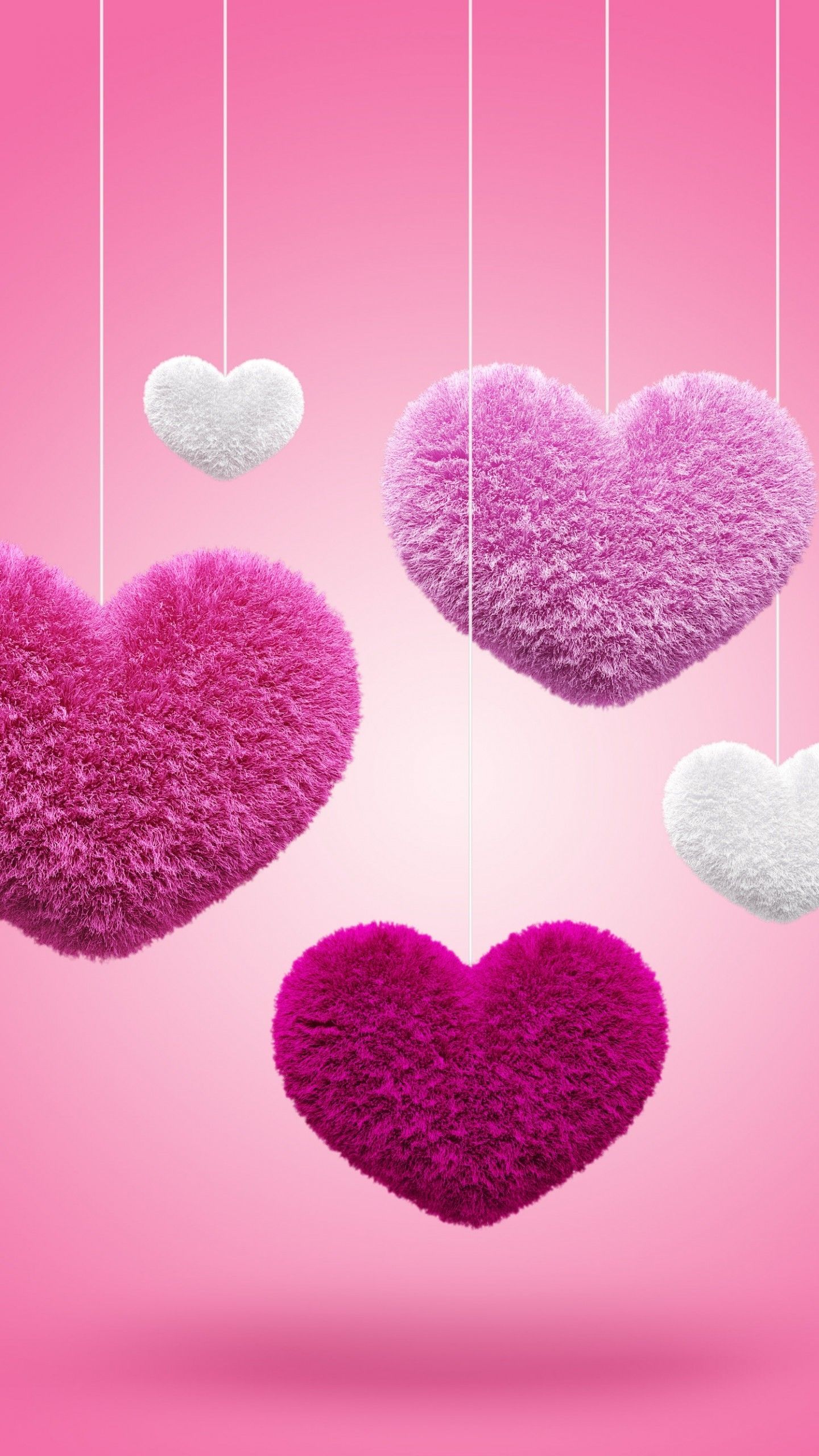 Fluffy pink and white hearts hanging on strings against a pink background