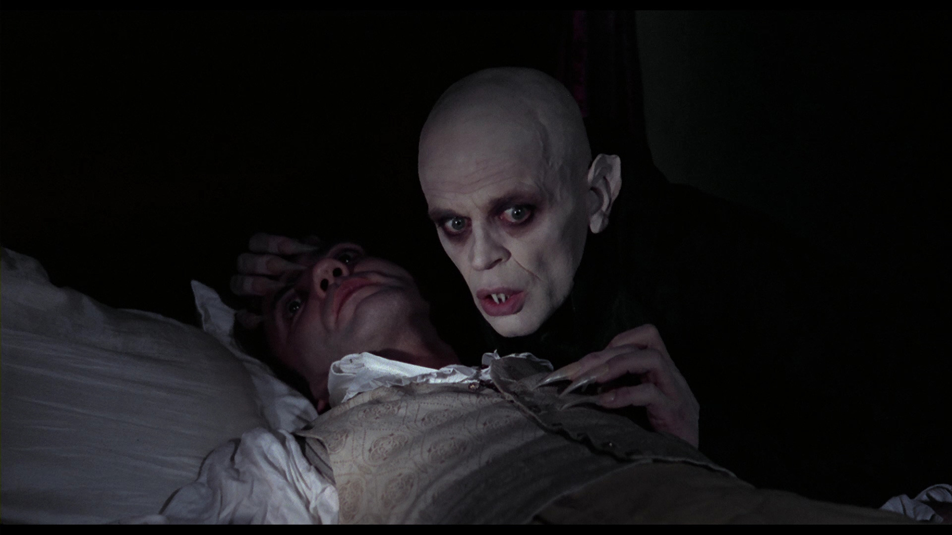 A chilling scene from Nosferatu (1922) featuring Count Orlok looming over his victim