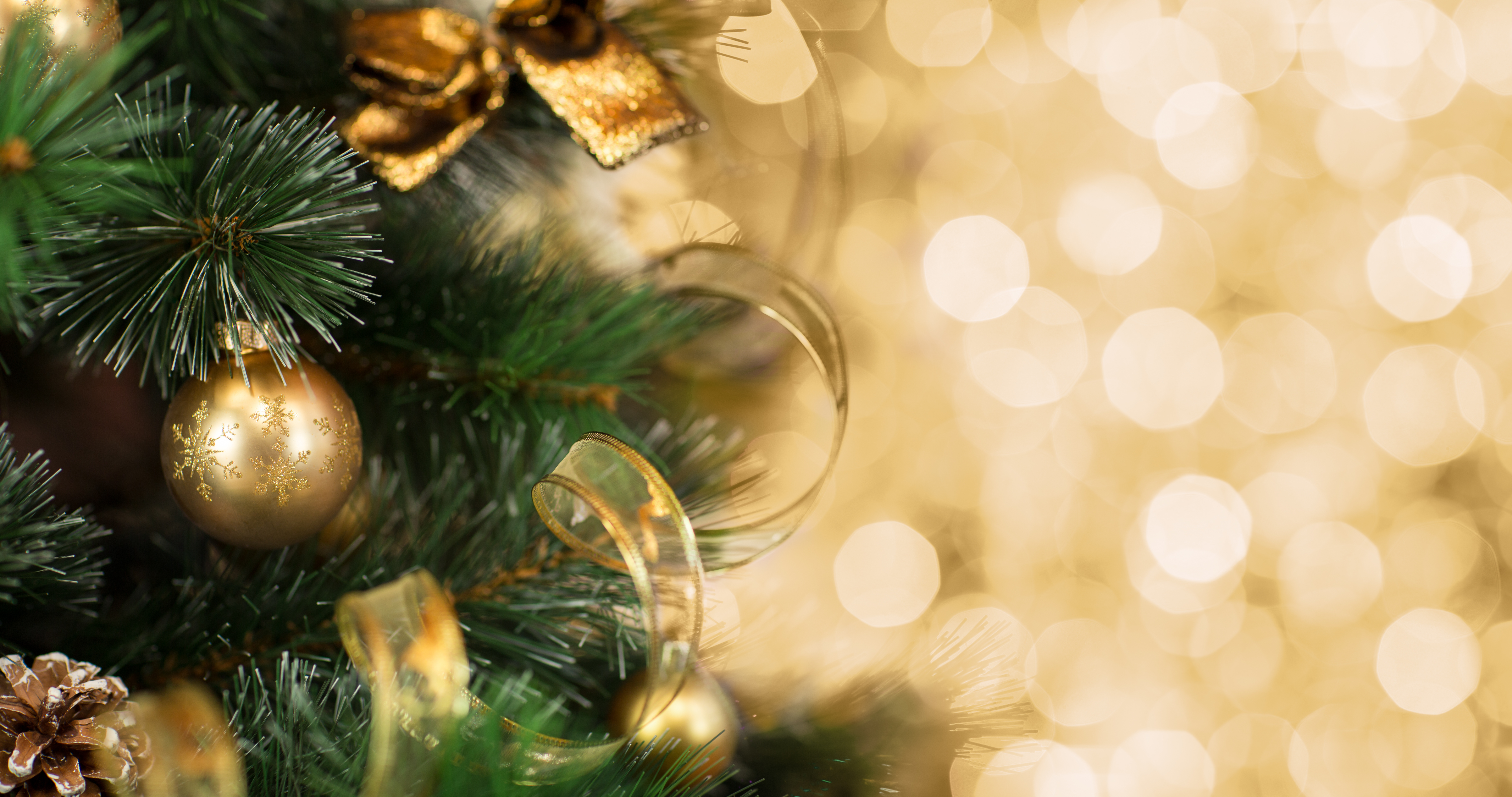 Close-up of a decorated Christmas tree with gold ornaments, ribbons, and a bokeh background, perfect for a festive holiday theme