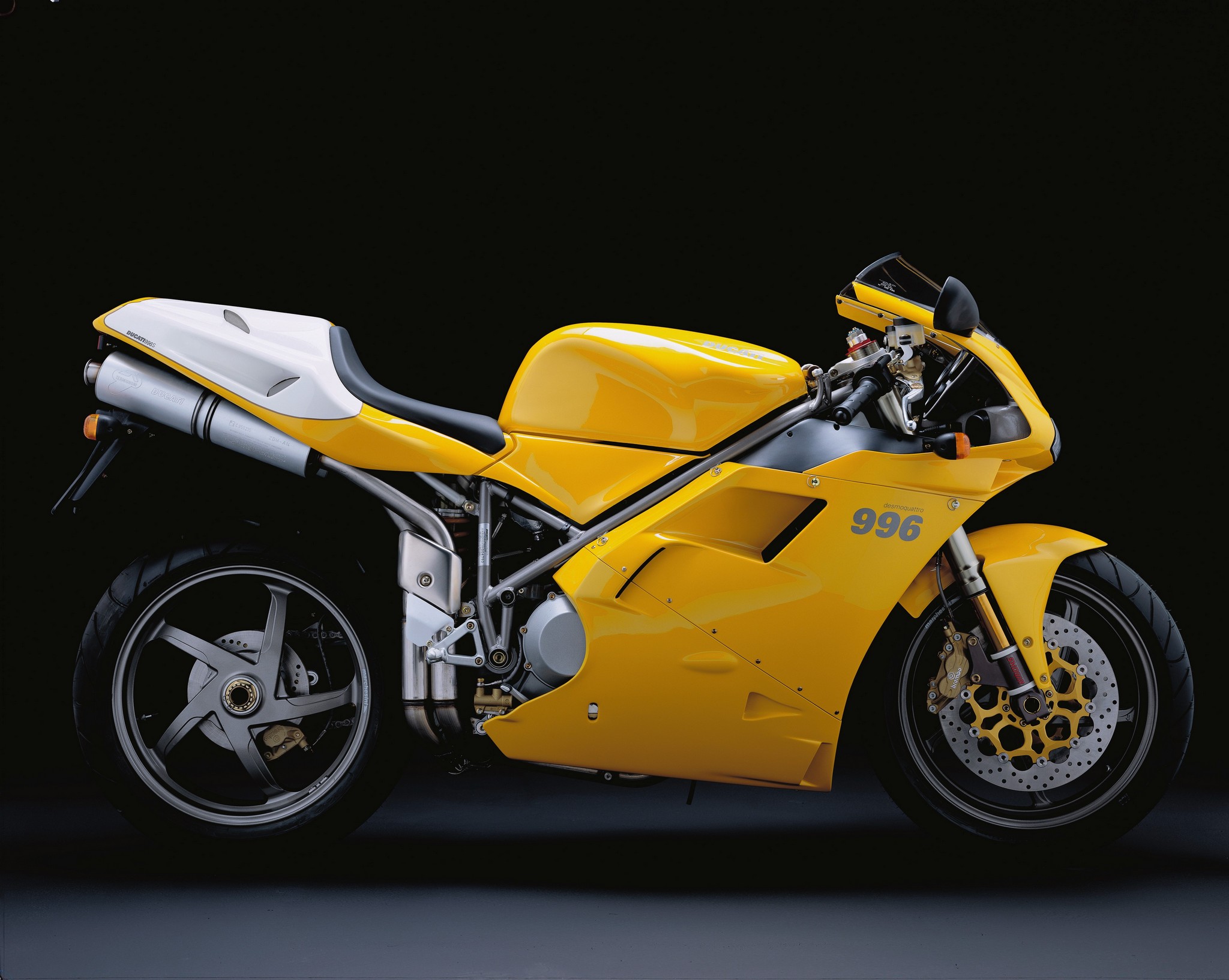 A vibrant yellow Ducati 996 motorcycle against a dark background, showcasing its sporty design and powerful presence