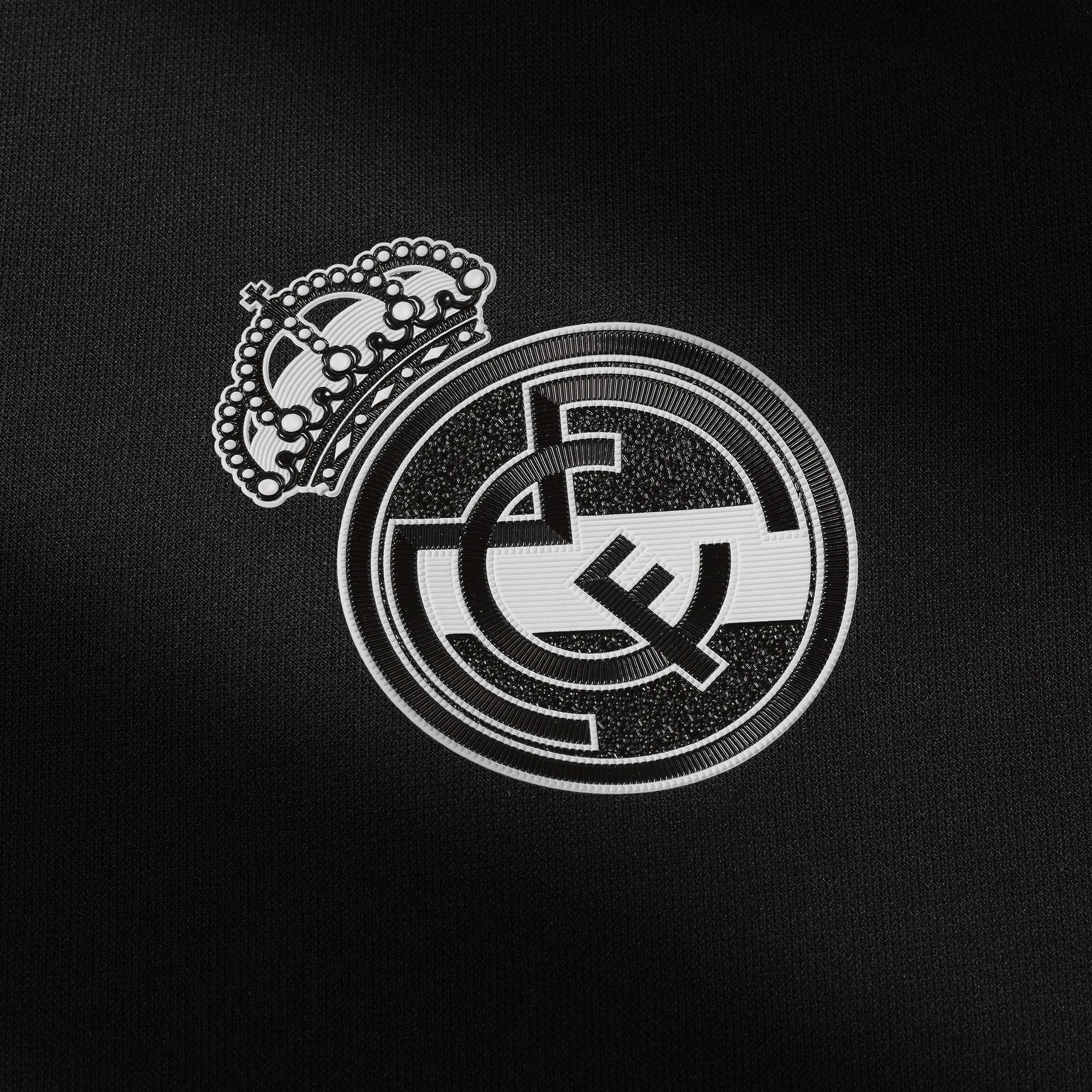 Close-up of the Real Madrid logo on a black jersey, showcasing the intricate details of the crown and emblem