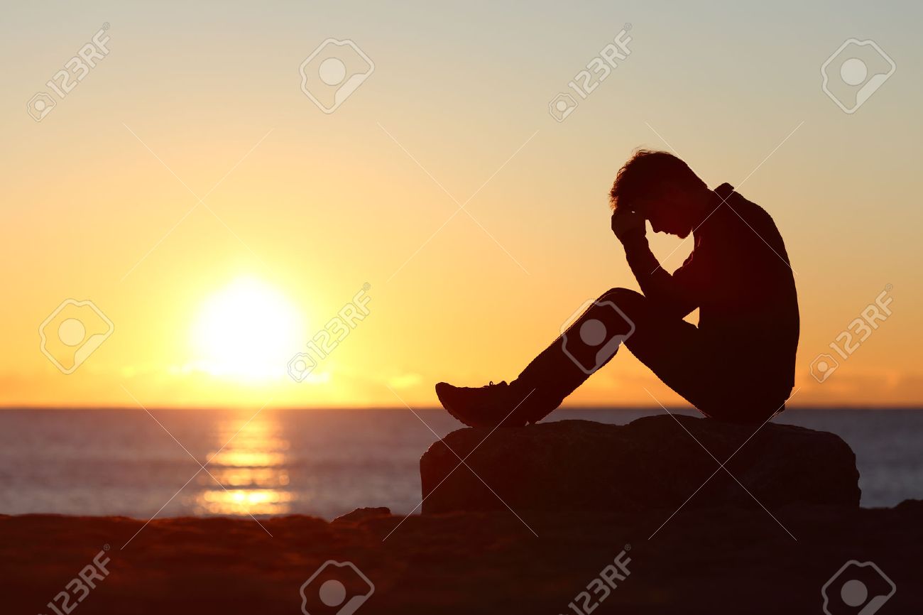 Sad Man Silhouette Worried On The Beach At Sunset With Sun