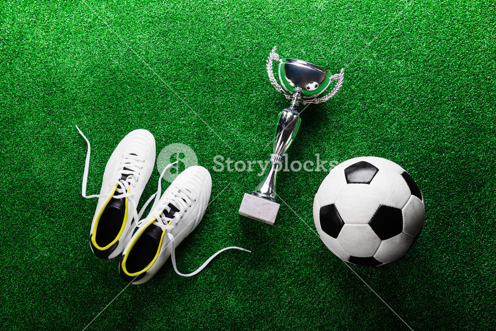 Soccer Ball Cleats And Trophy Against Artificial Turf Studio
