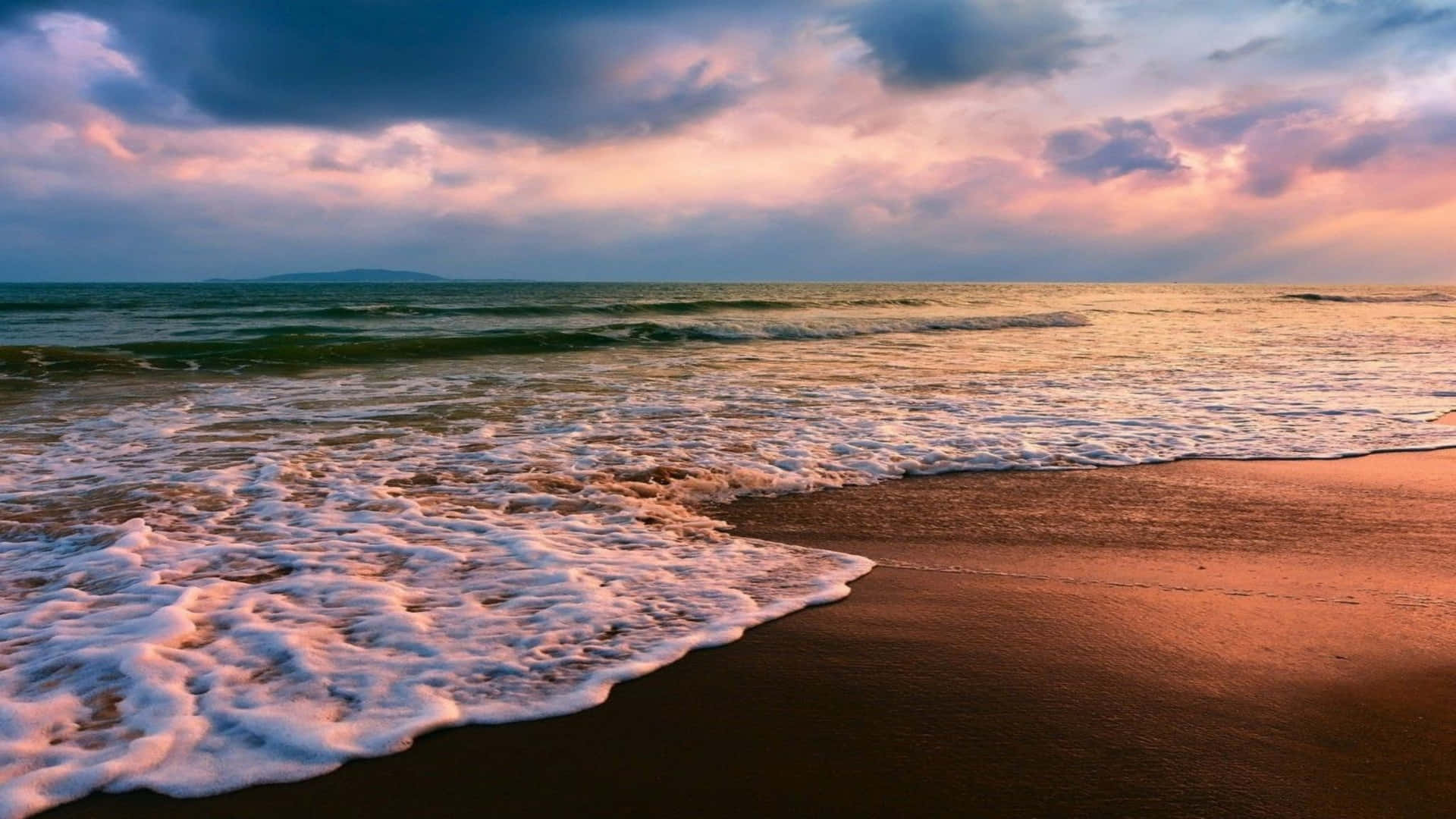 Sunset at the beach with waves gently rolling onto the shore