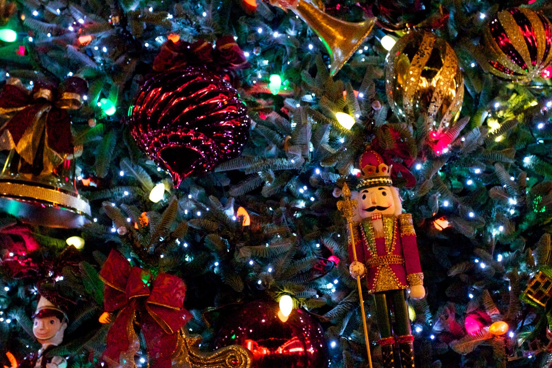 Close-up of a Christmas tree adorned with ornaments, lights, and a nutcracker, evoking the festive spirit of the holiday season