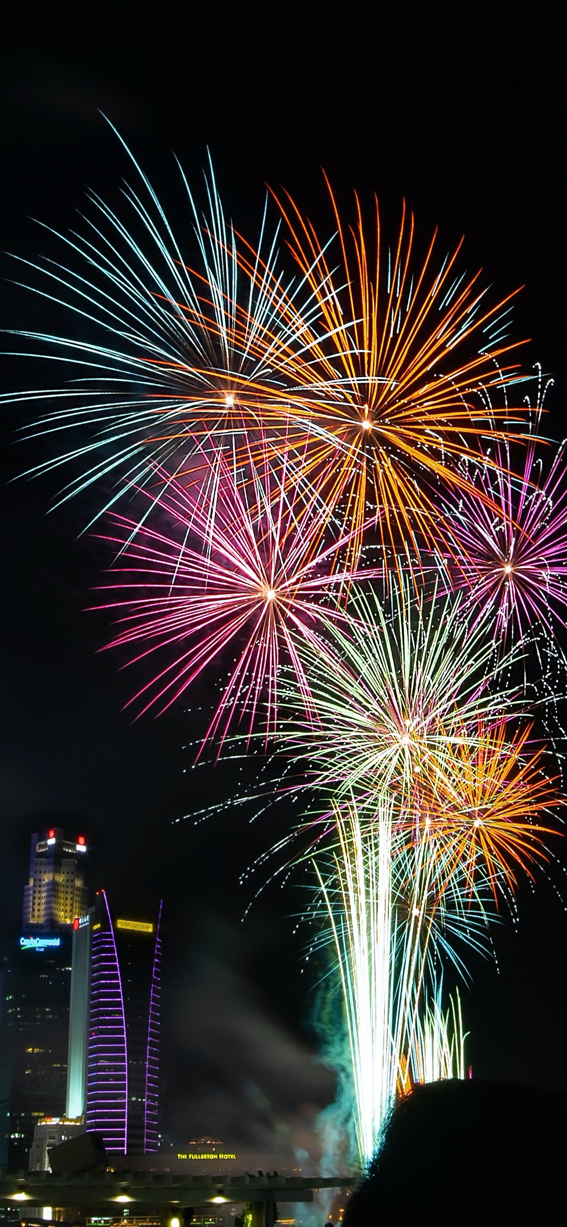 Fireworks light up the night sky over a cityscape, celebrating New Year's Eve