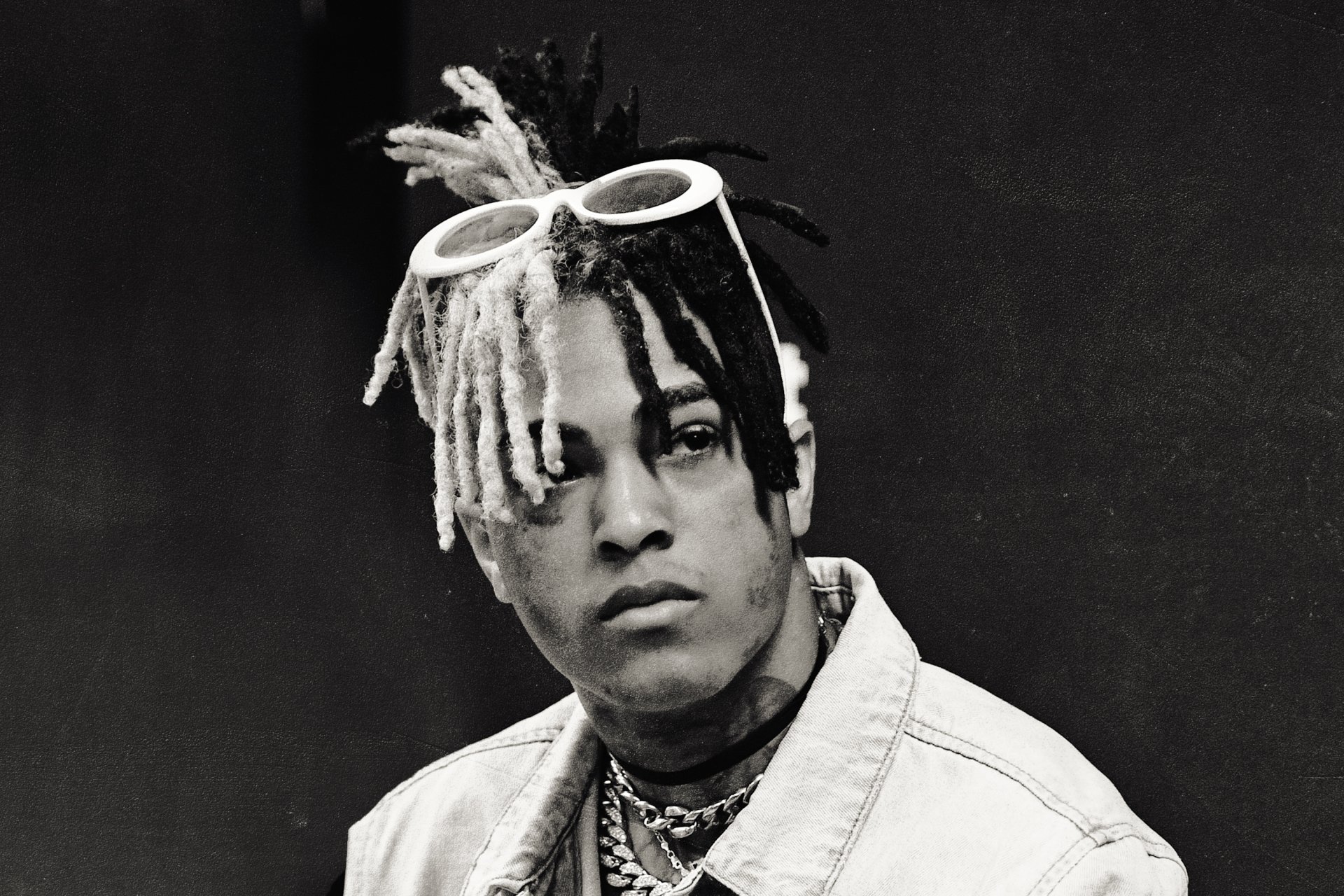 Black and white close-up portrait of XXXTentacion, showcasing his unique hairstyle and glasses