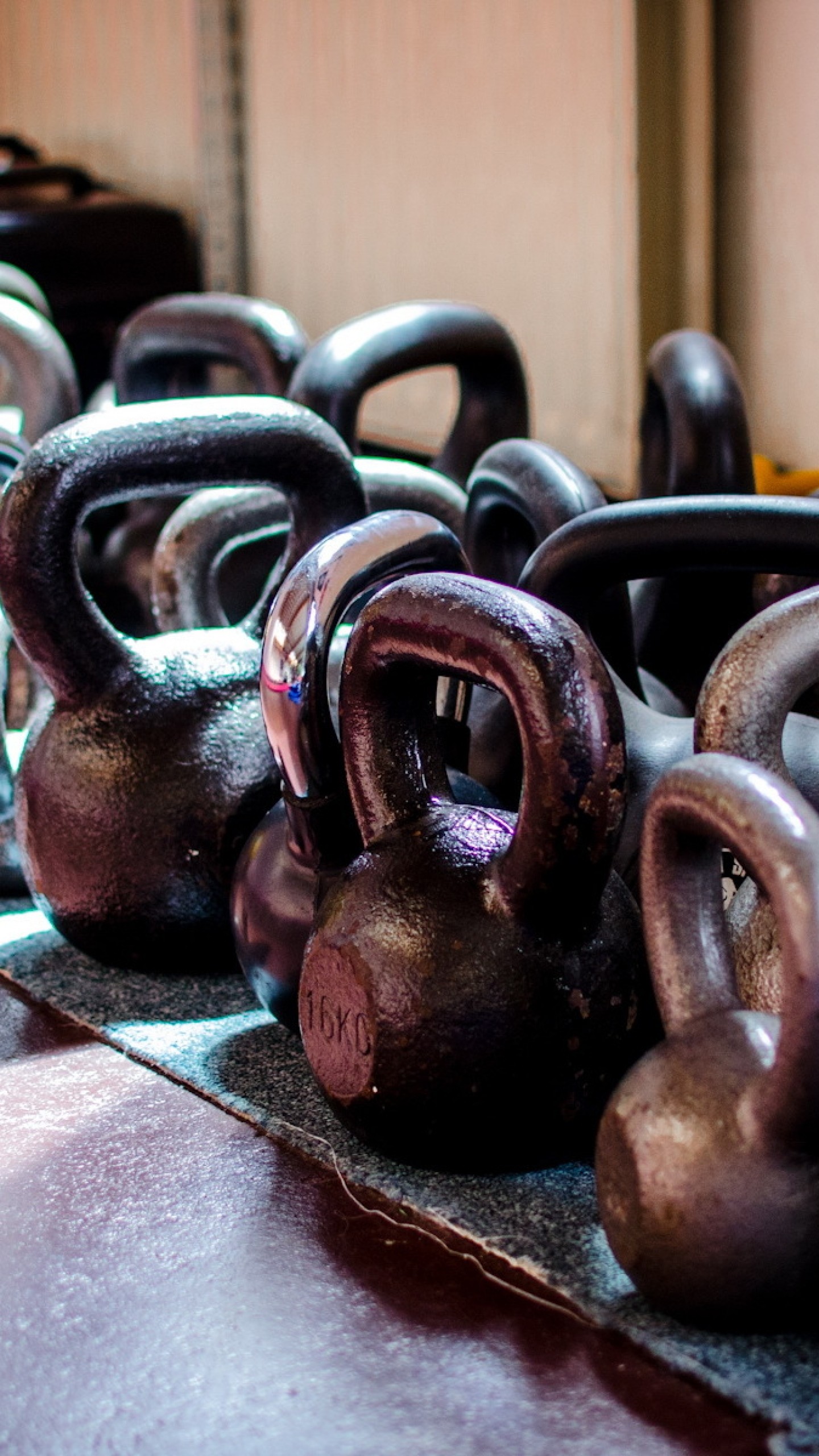 A close-up view of a row of kettlebells on a gym floor, ready for a CrossFit workout