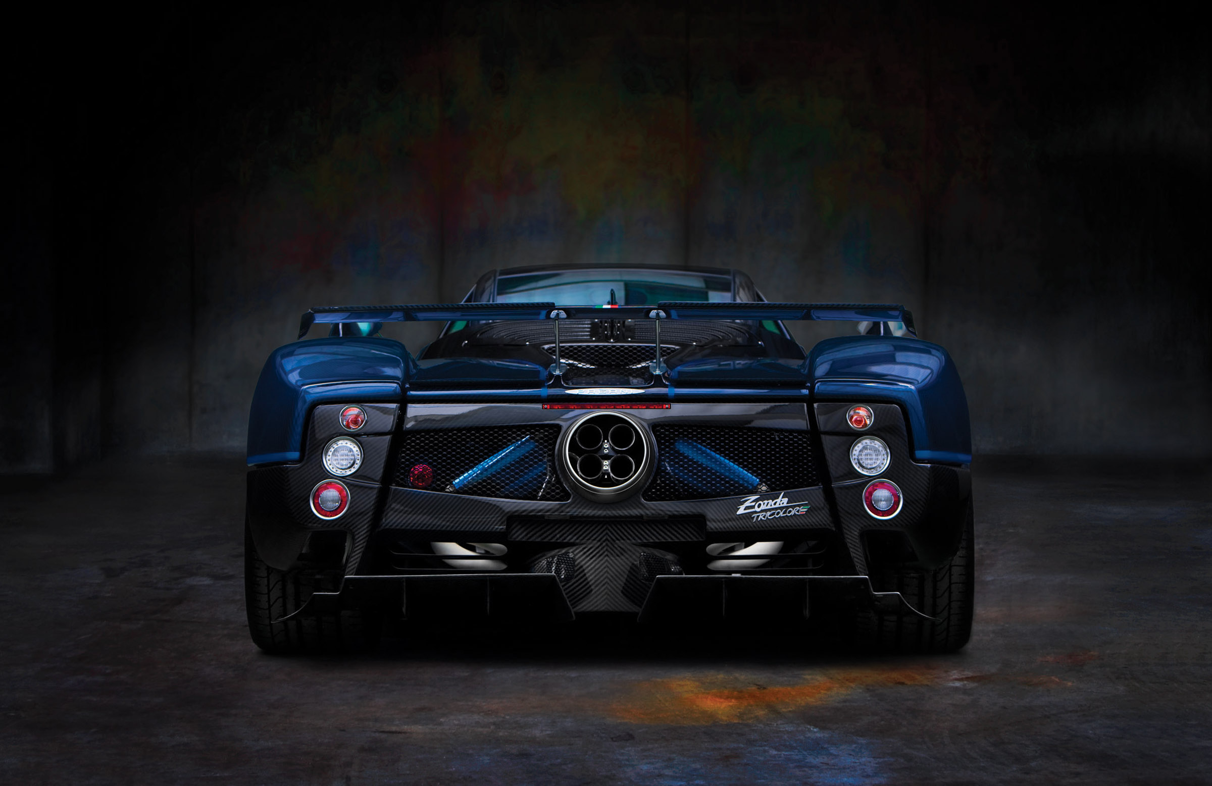Rear view of a Pagani Zonda Tricolore supercar in a dark garage